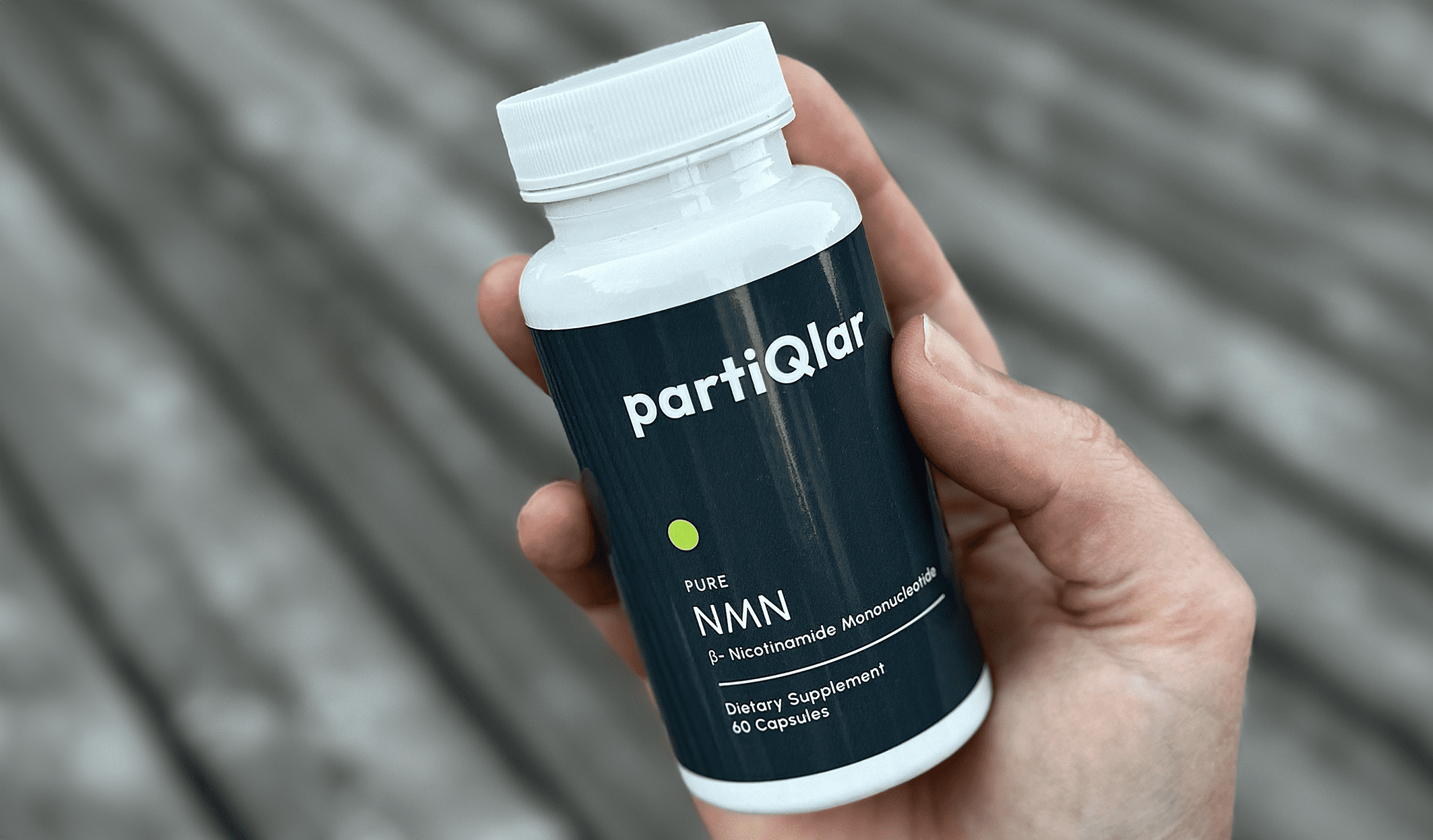 Hand holding partiQlar Pure NMN product bottle on a white background