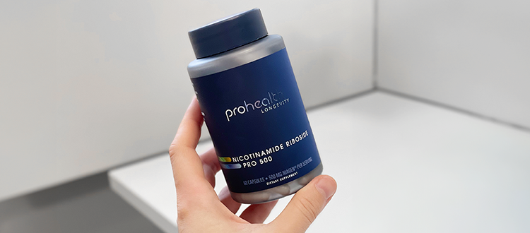 Hand holding a ProHealth Nicotinamide Riboside Pro bottle against a gray wall in the background