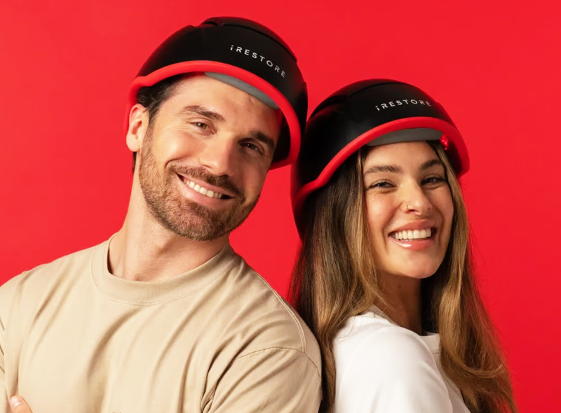 Two people wearing iRestore Elite devices set against a red background