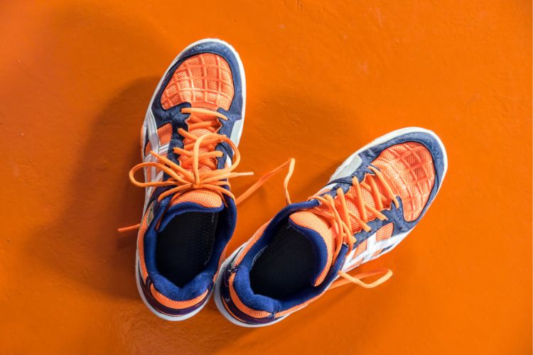 orange and blue running shoes on orange background