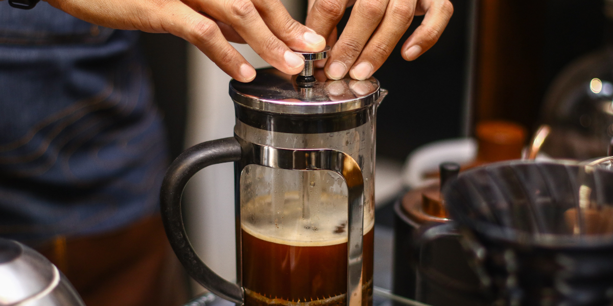 A person making coffee with a French press.