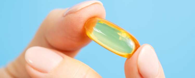 Close-up of hand hand holding omega 3 fish oil capsule. Vitamin pill or supplement