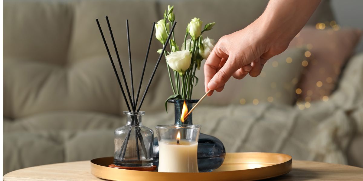 Person lighting paraffin wax candle at wooden table in living room