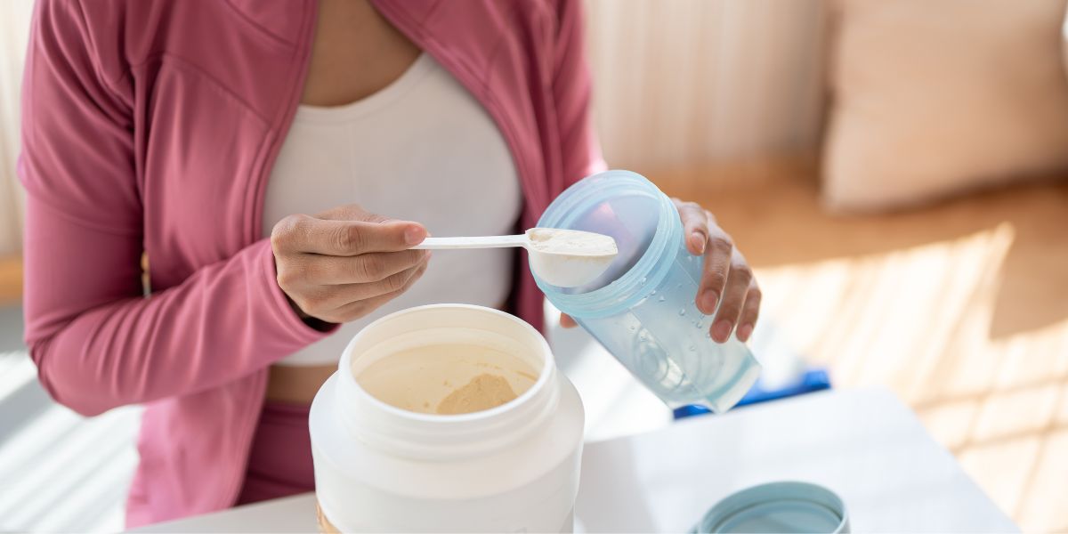 Close-up image of a person in sportswear making their protein shake after a workout at home.
