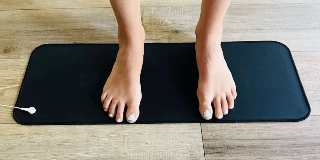 Persons legs standing on a black grounding mat on wooden floor