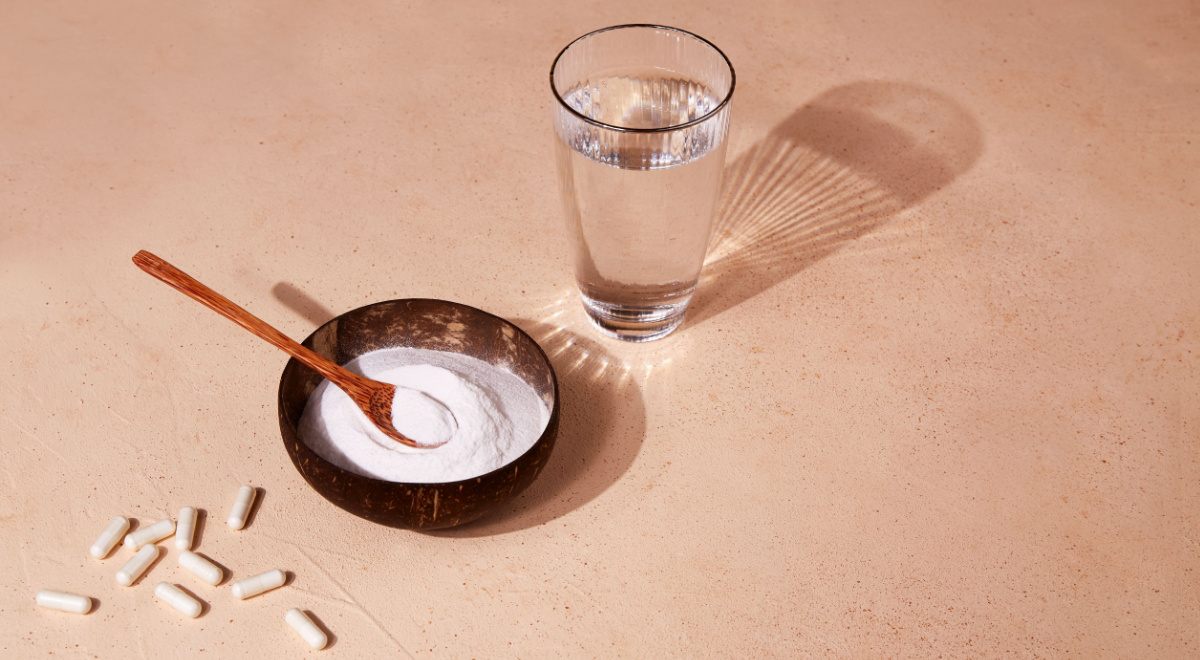 Collagen protein powder capsules and glass of water on a beige background