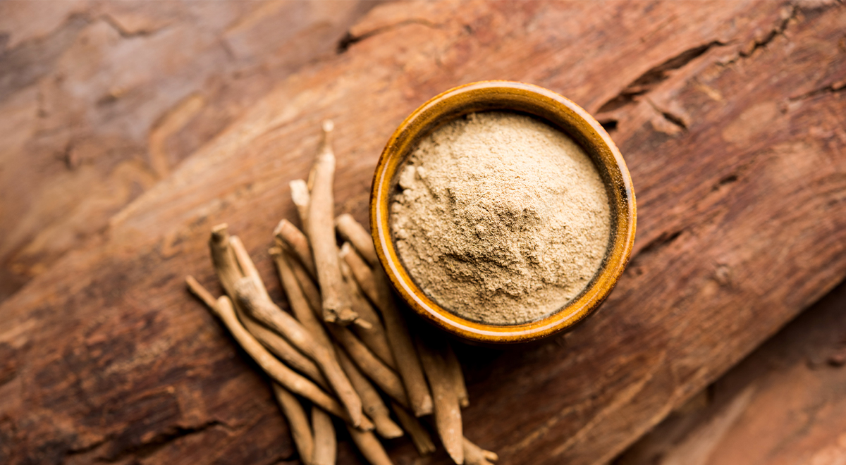 Ashwagandha root and powder on a dark wooden table in a wooden bowl