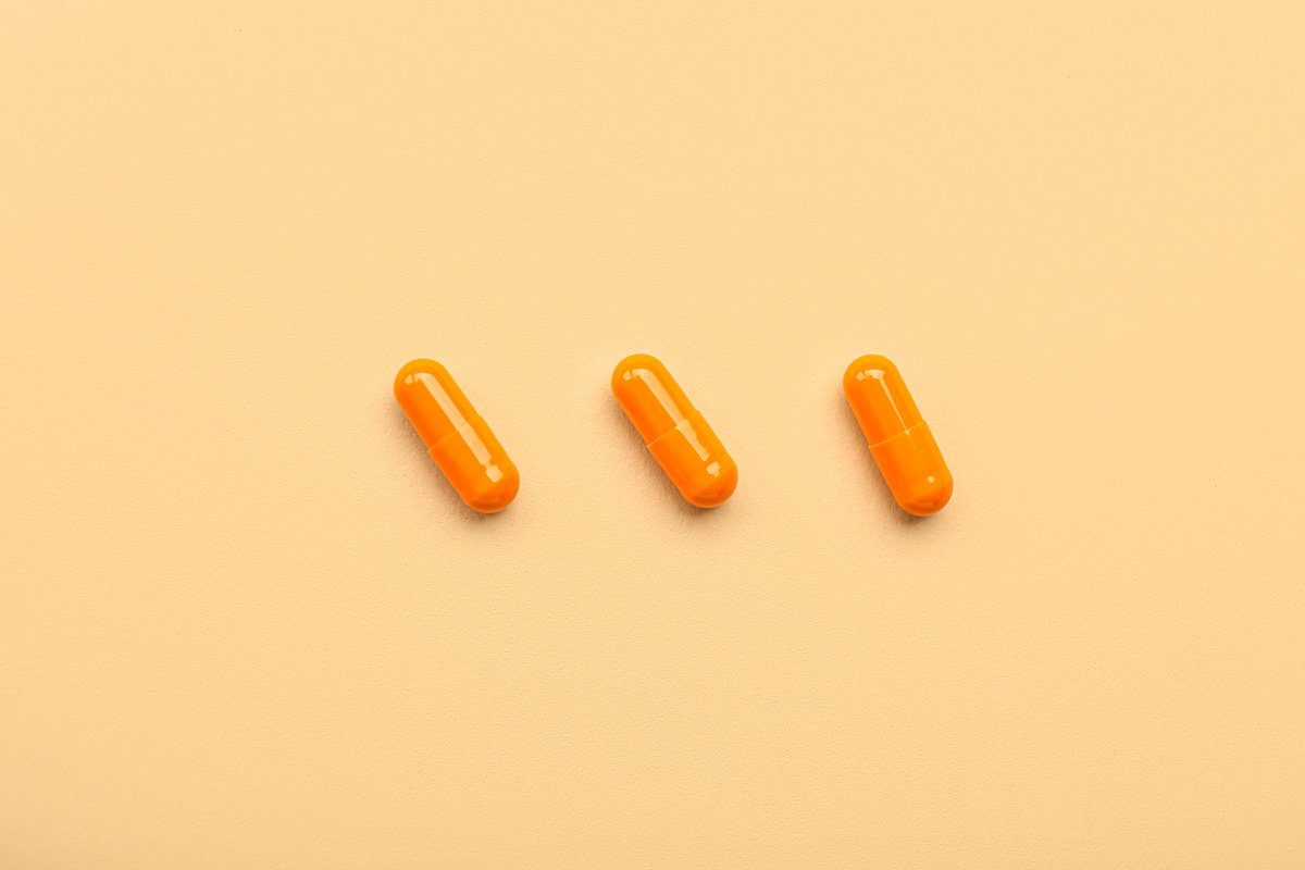 Orange medical capsules on beige background.