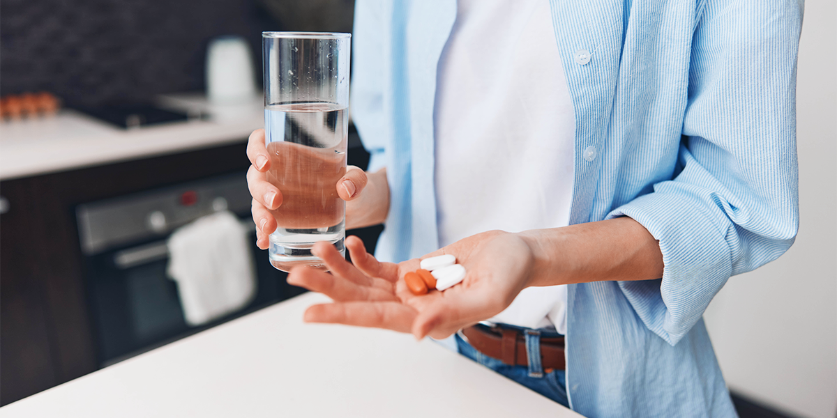 Person taking handful of supplements with water