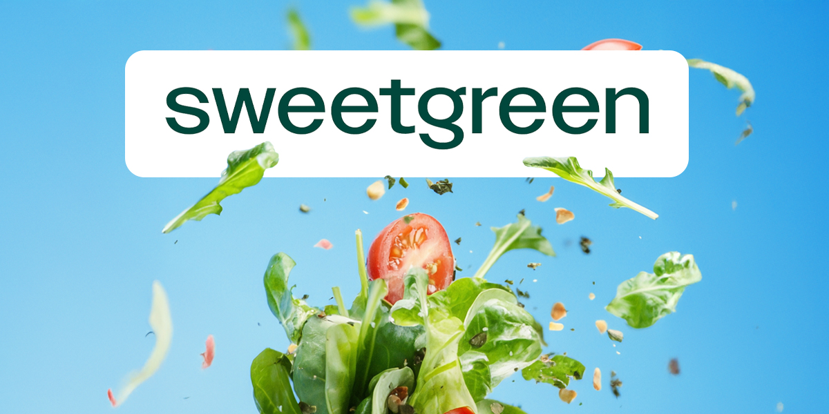 The word 'Sweetgreen' on a blue background with a splashing salad of tomatoes and spinach