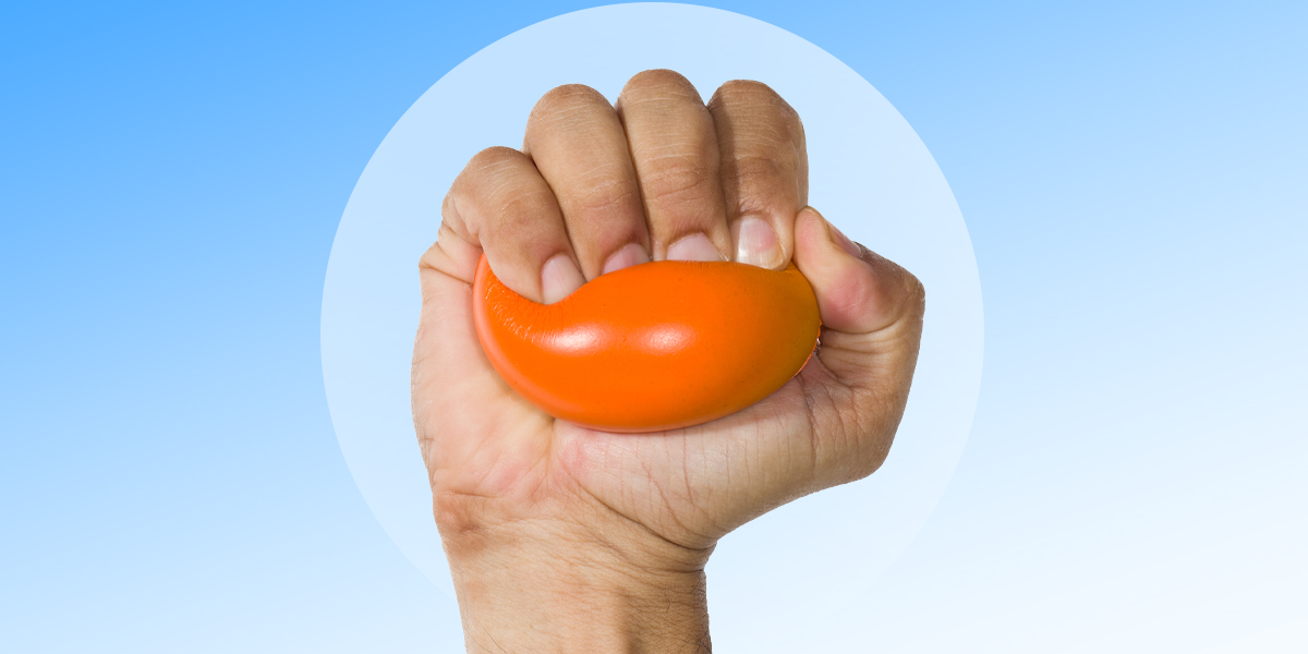 Hand squeezing a stress ball set against a blue background