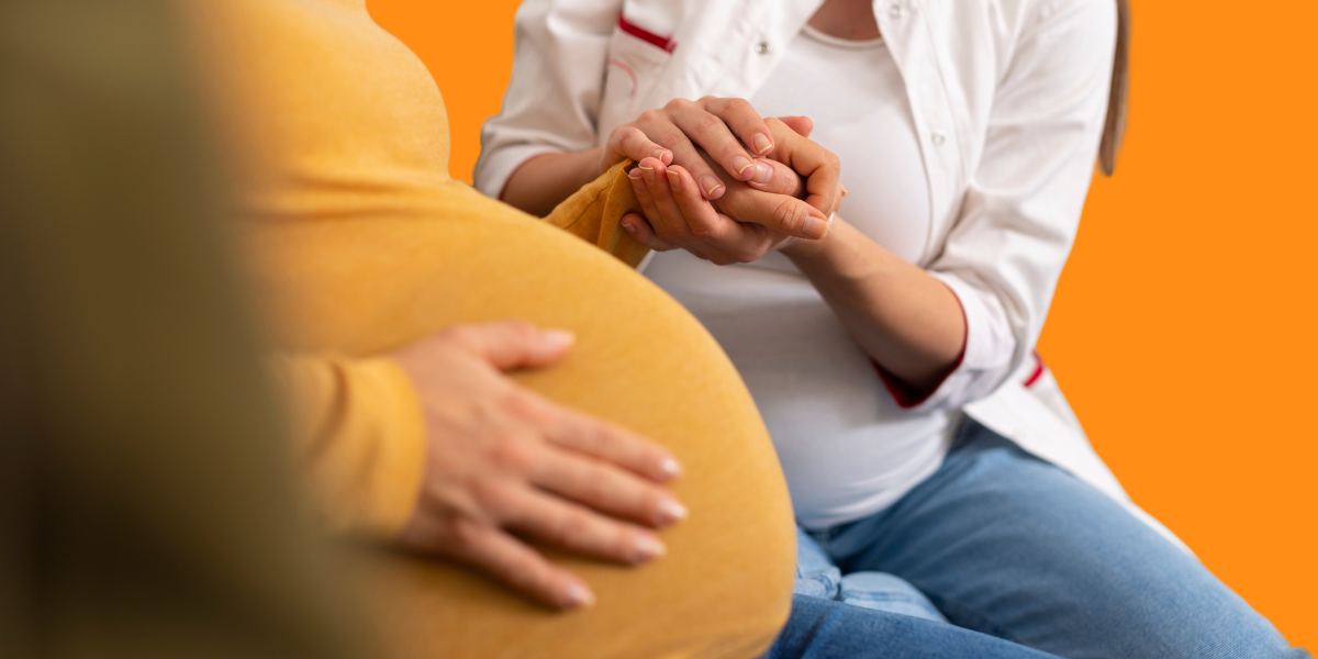 A healthcare professional holding a pregnant woman's hand