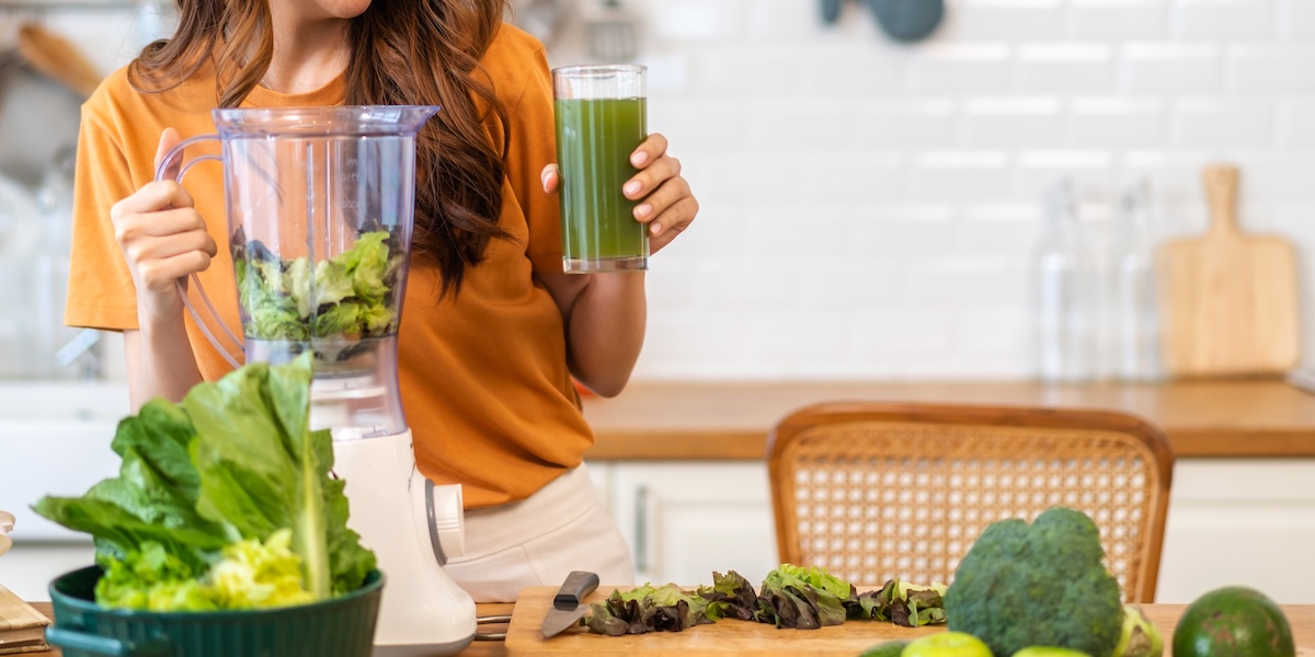 Woman blending green vegetables to make juice