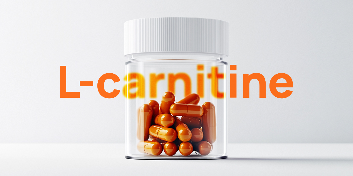 Orange L-carnitine pills in a glass container on a table grey white background