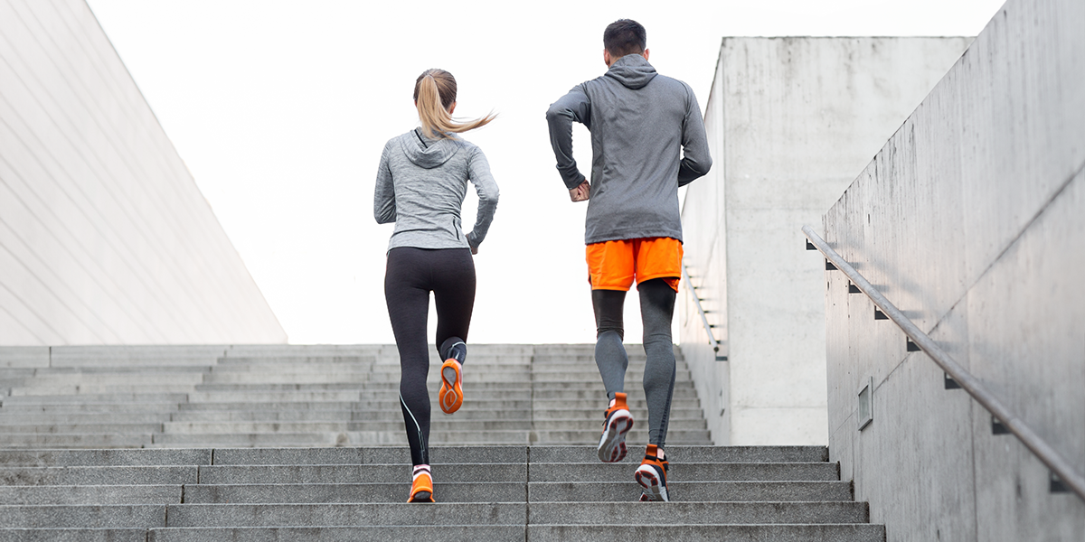 Two people running up the stairs outside in gym clothes