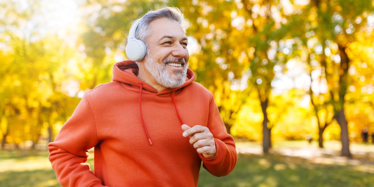 happy older man wearing orange sweatshirt jogging outdoors
