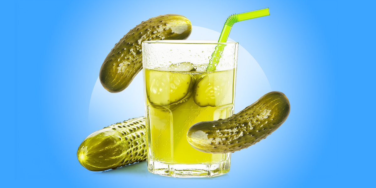 A glass of pickle juice surrounded my pickles with a blue background