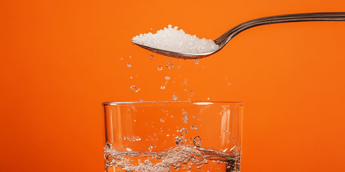 Pouring a spoonful of salt into a glass of water