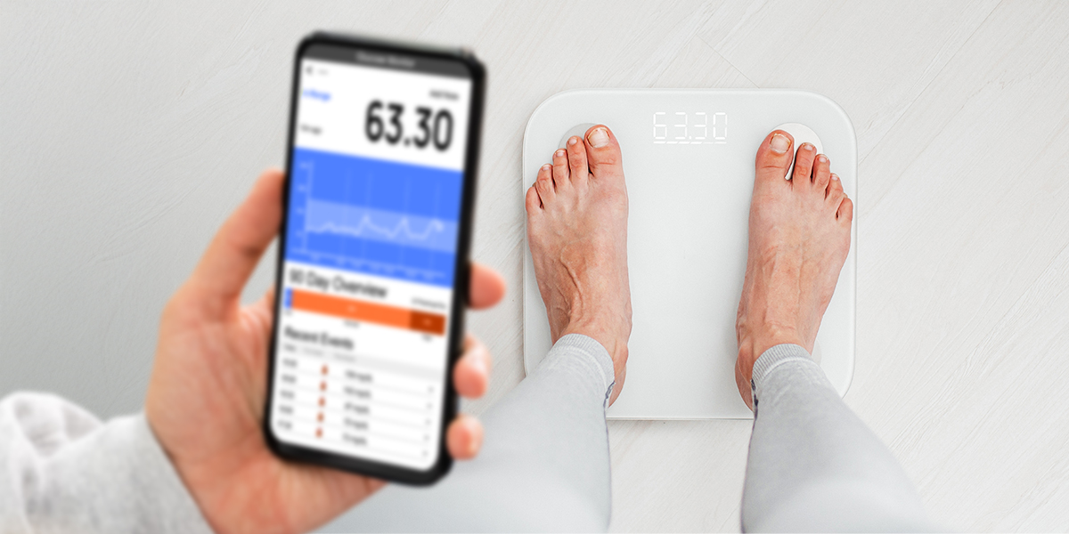 Person standing on a smart scale and checking the result on their phone