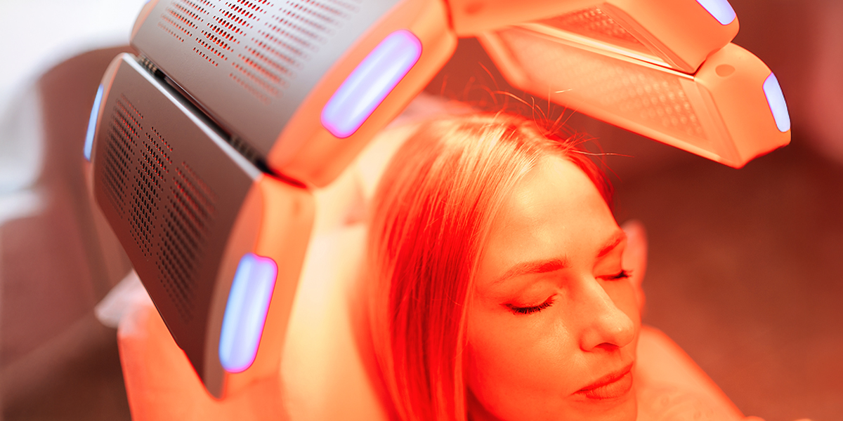 Person using a red light therapy device for their hair and scalp