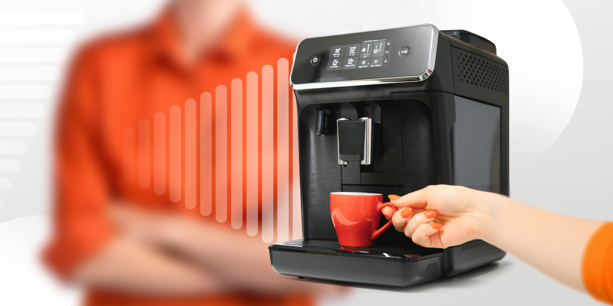 A person's hand holding a cup next to a coffee machine