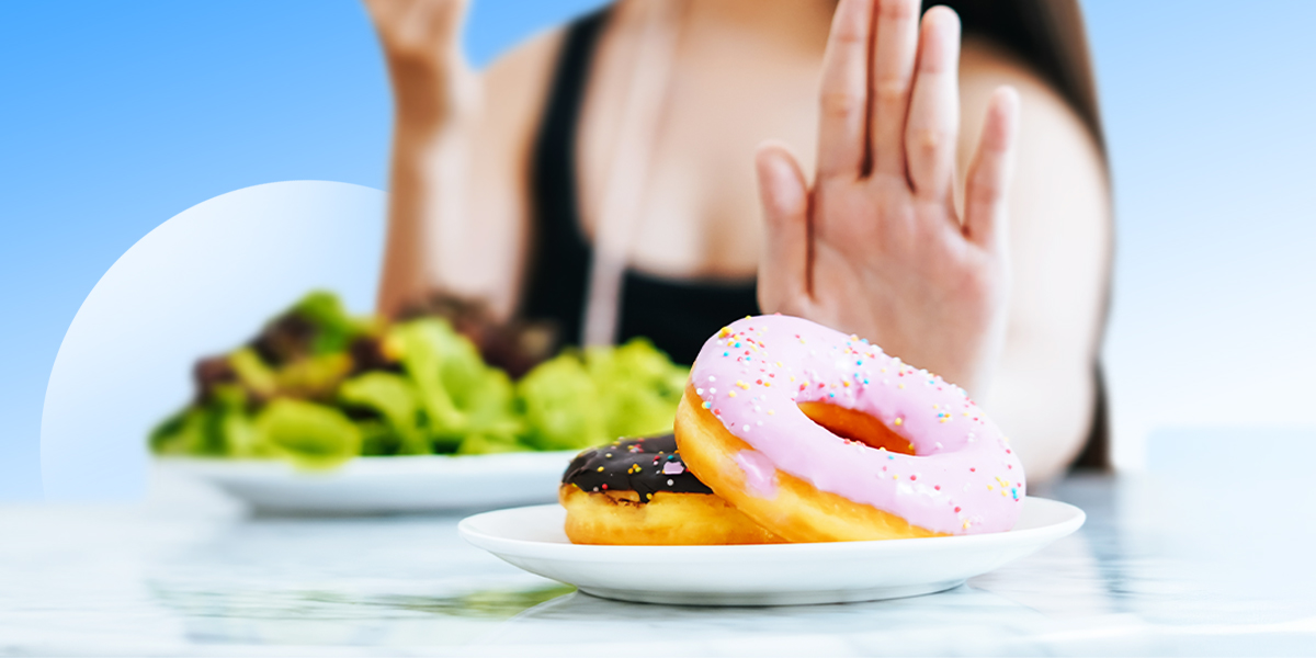 Person behind the table saying no to donuts with a healthy plate in background