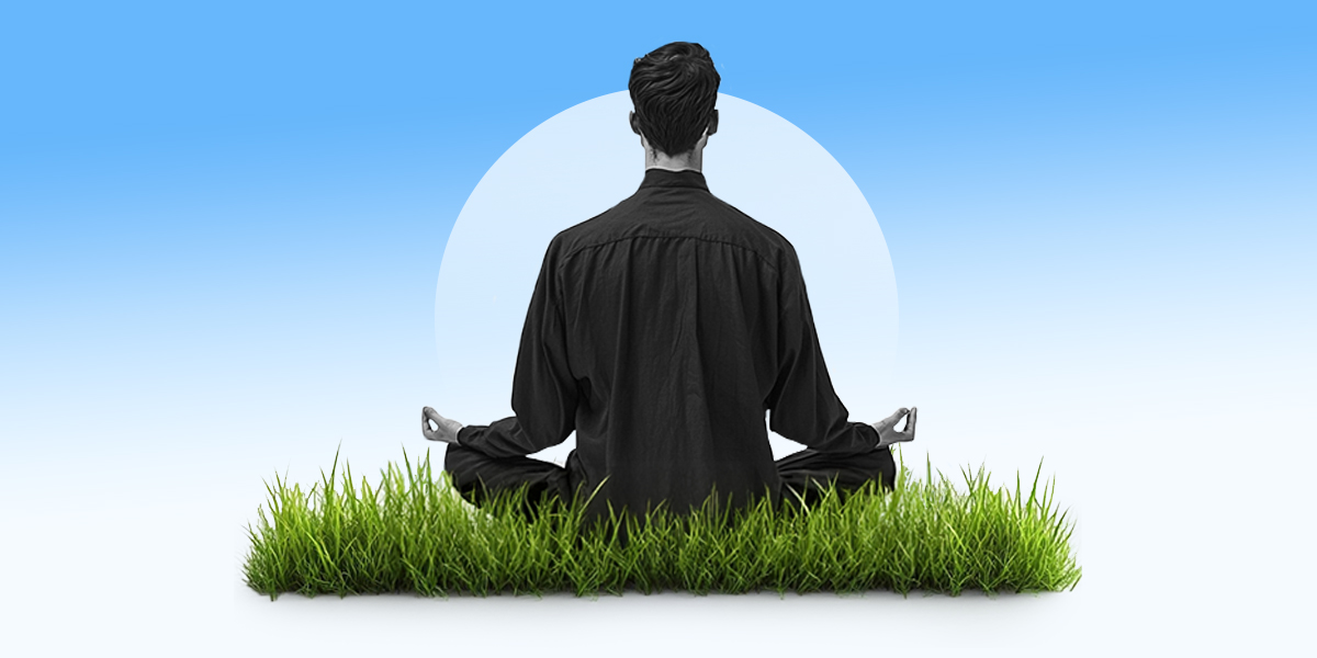 Person sitting on grass meditating back turned, blue background