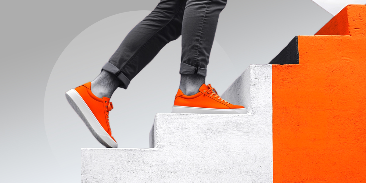 Person climbing a staircase, wearing bright orange shoes