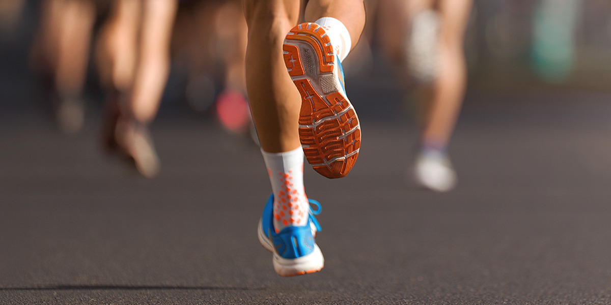Feet wearing orange and bleu sneakers running in a marathon