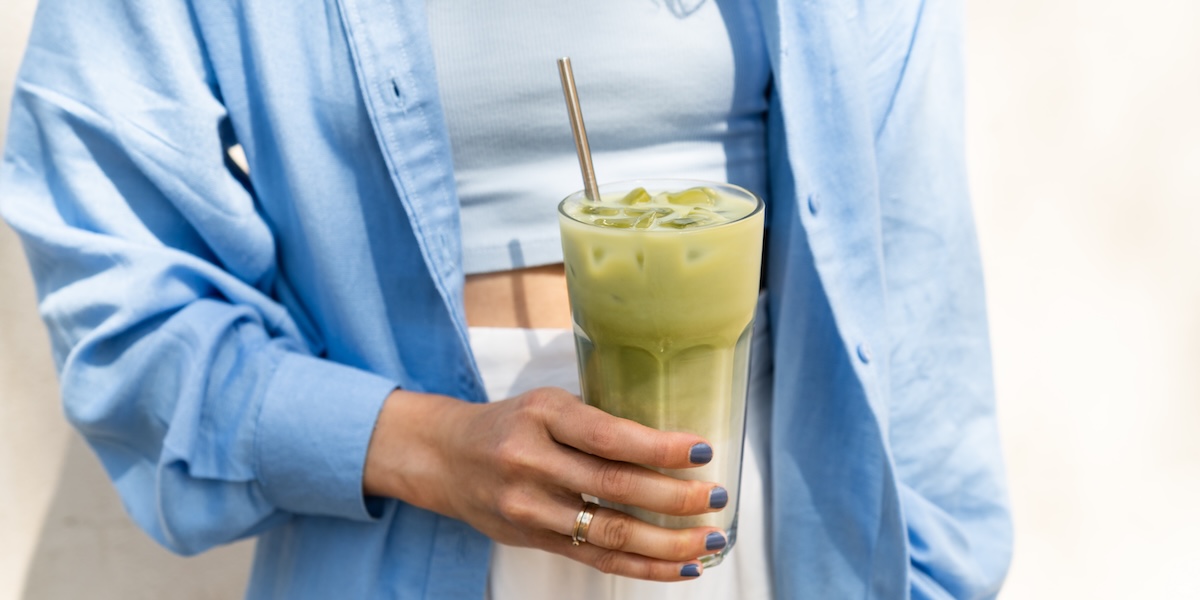 A hand holding an iced matcha latte