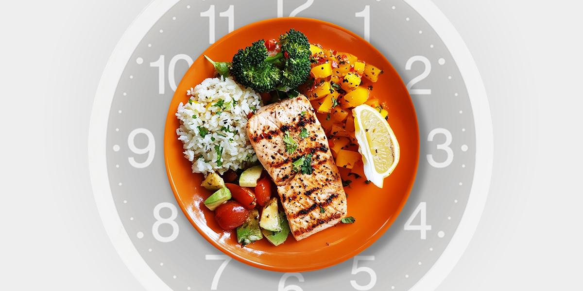 Orange plate full of omad diet food with clock in the background