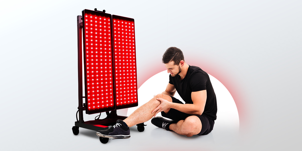 Person on the ground feeling their knee for pain next to a big red light device