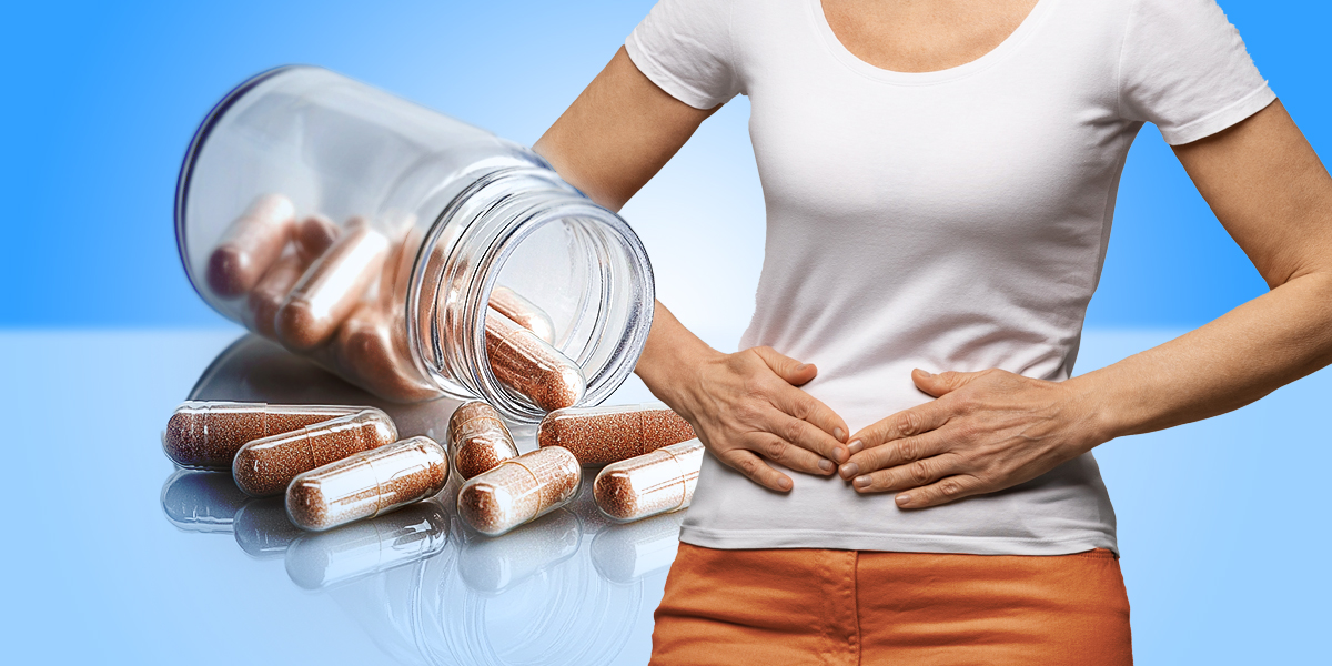 Person feeling their stomach while pills from a bottle come out in a background