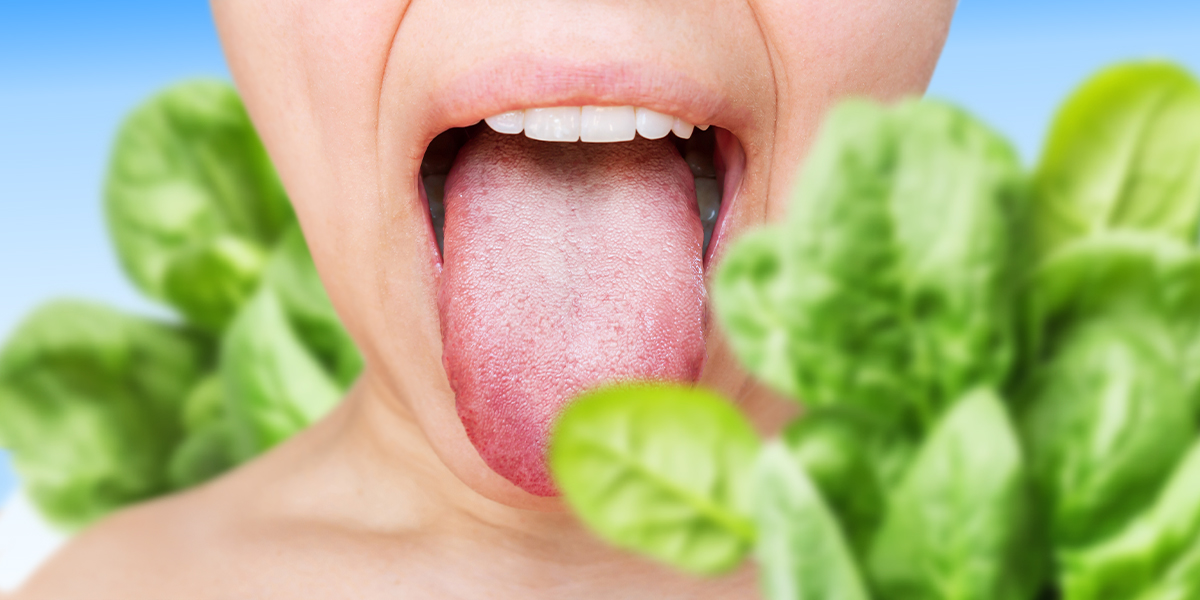 A person with their mouth wide open surrounded by spinach leaves