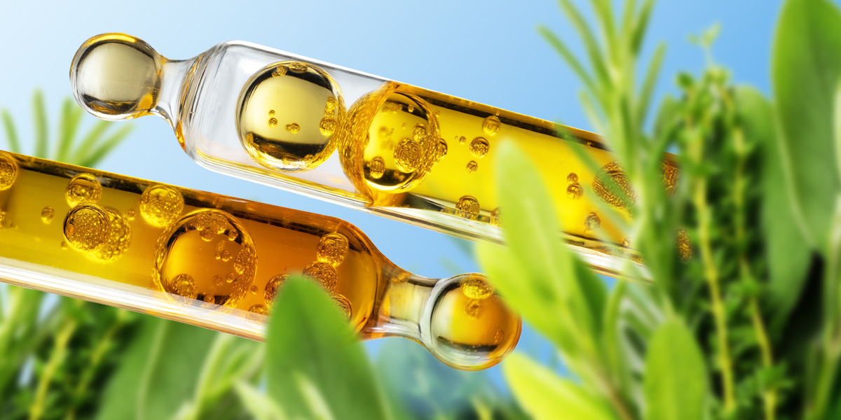 Two ampules of yellow liquid and green plants on a blue background