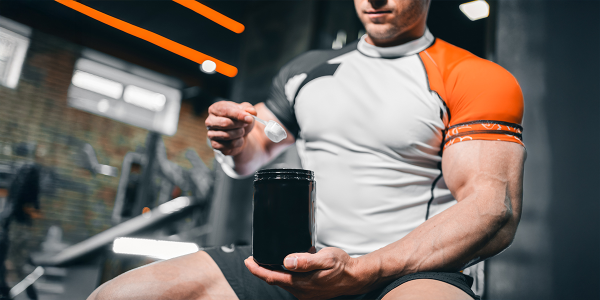 Person scooping a creatine supplement in a gym environment