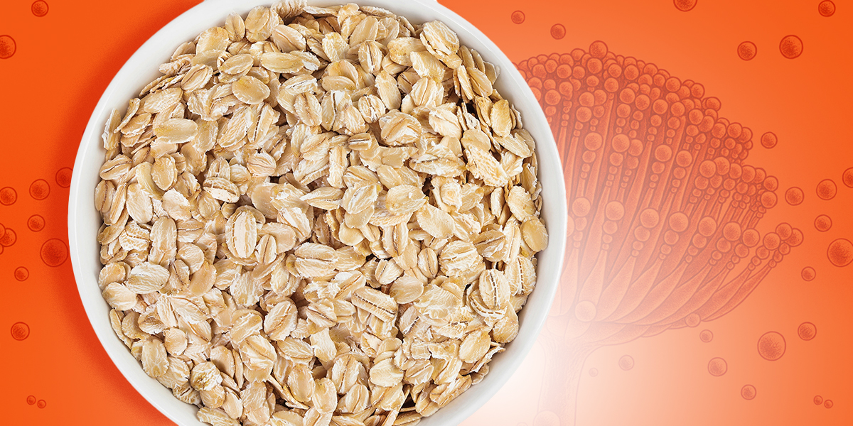 A bowl with raw oats on an orange background