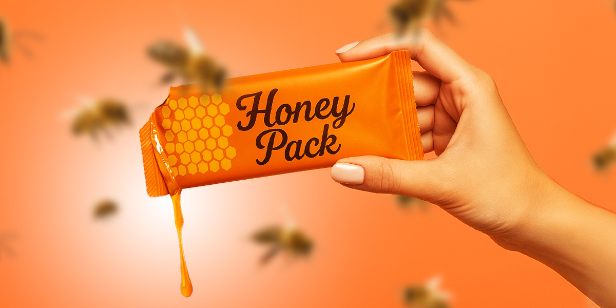 Hand holding a honey pack in orange background