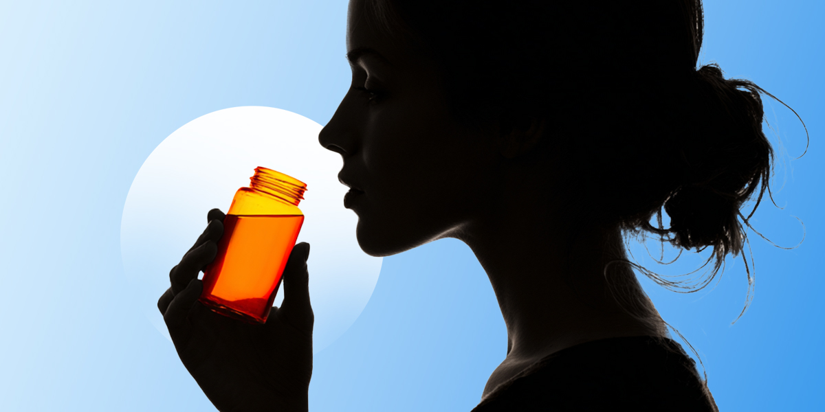 A silhouette of a person drinking an orange supplement shot