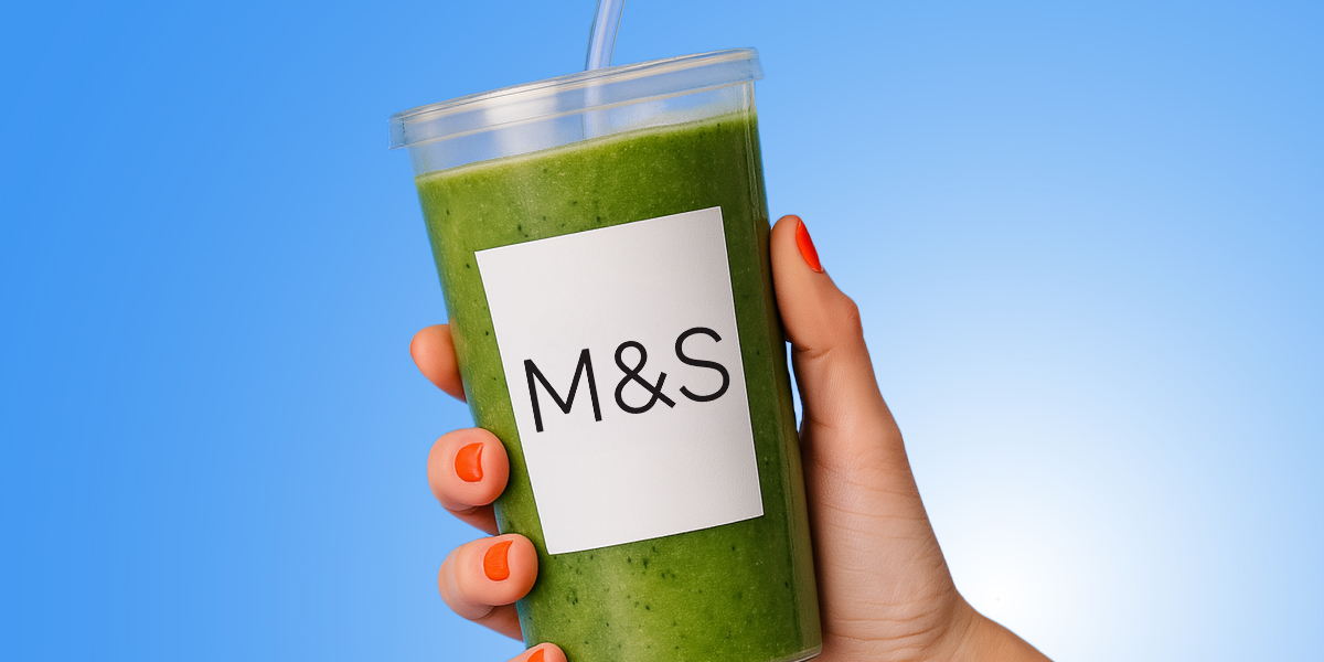 A hold holding a glass of green juice