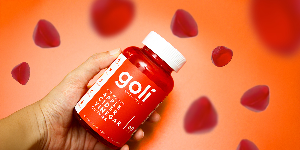 A hand holding a bottle of Goli apple cider vinegar gummies