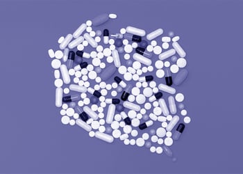 Dozens of pills on a violet background.