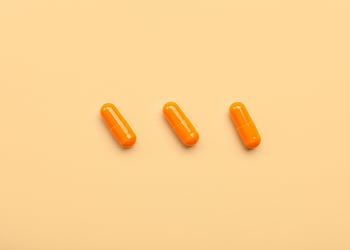 Orange medical capsules on beige background.