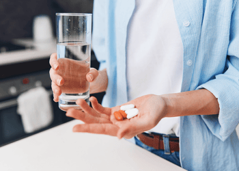 Person taking handful of supplements with water