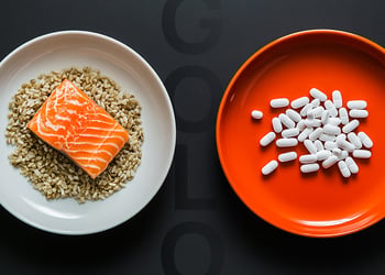 Two plates: one with salmon and grains, one with pills