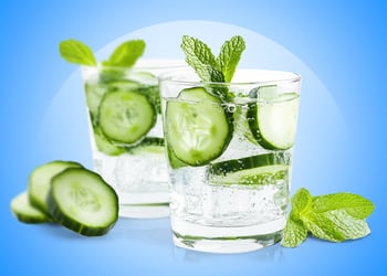 Sliced pickles in a glass cup of water blue background