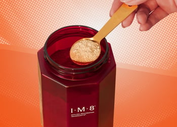 Spoon pulled from a bottle of All-in-One Supplement by David Beckham on an orange background