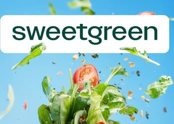 The word 'Sweetgreen' on a blue background with a splashing salad of tomatoes and spinach