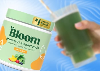 A bottle of Bloom Greens & Superfoods supplement and a hand holding a green smoothie