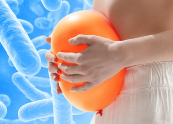 Persons belly hugging orange balloon with blue probiotic background